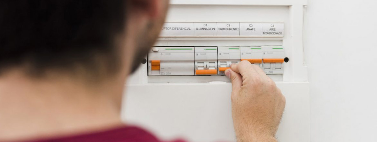 Un hombre joven mirando el cuadro eléctrico tras una de las verificaciones eléctricas periódicas