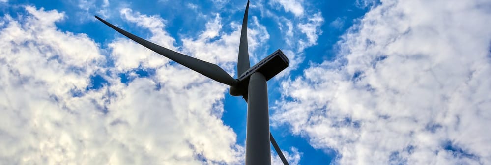 Aerogenerador de un parque eólico y fondo con cielo azul y nubes