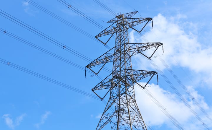 torre eléctrica con cielo azul y nubes de fondo